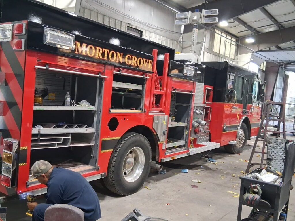 Morton Grove Fire Department Engine 5 undergoing professional fire truck body repair with compartments opened during the restoration process.